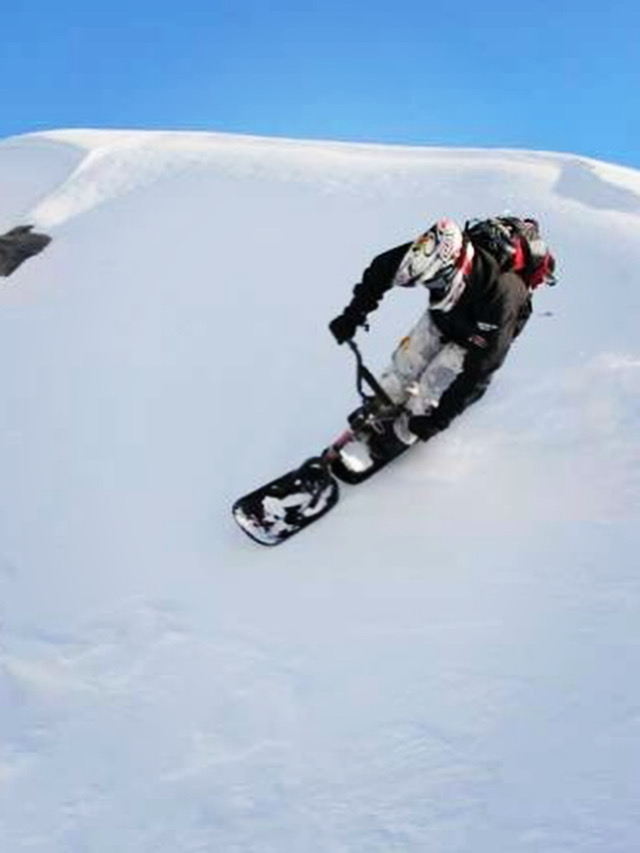 Rider carving deep powder on a RIP ski bike